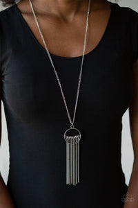Infused with a shimmery silver chain fringe, a row of gray beads is threaded along a silver rod that is fitted in place inside the center of an airy silver ring. The colorful pendant swings from the bottom of a lengthened silver chain for a trendy tribal look. Features an adjustable clasp closure.  Sold as one individual necklace. Includes one pair of matching earrings.  Always nickel and lead free.