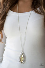 Load image into Gallery viewer, An over sized golden teardrop gem swings from the top of a glistening silver teardrop frame. The dramatic pendant swings from the bottom of an elegantly elongated silver chain for a regal finish. Features an adjustable clasp closure.  Sold as one individual necklace. Includes one pair of matching earrings.  Always nickel and lead free.