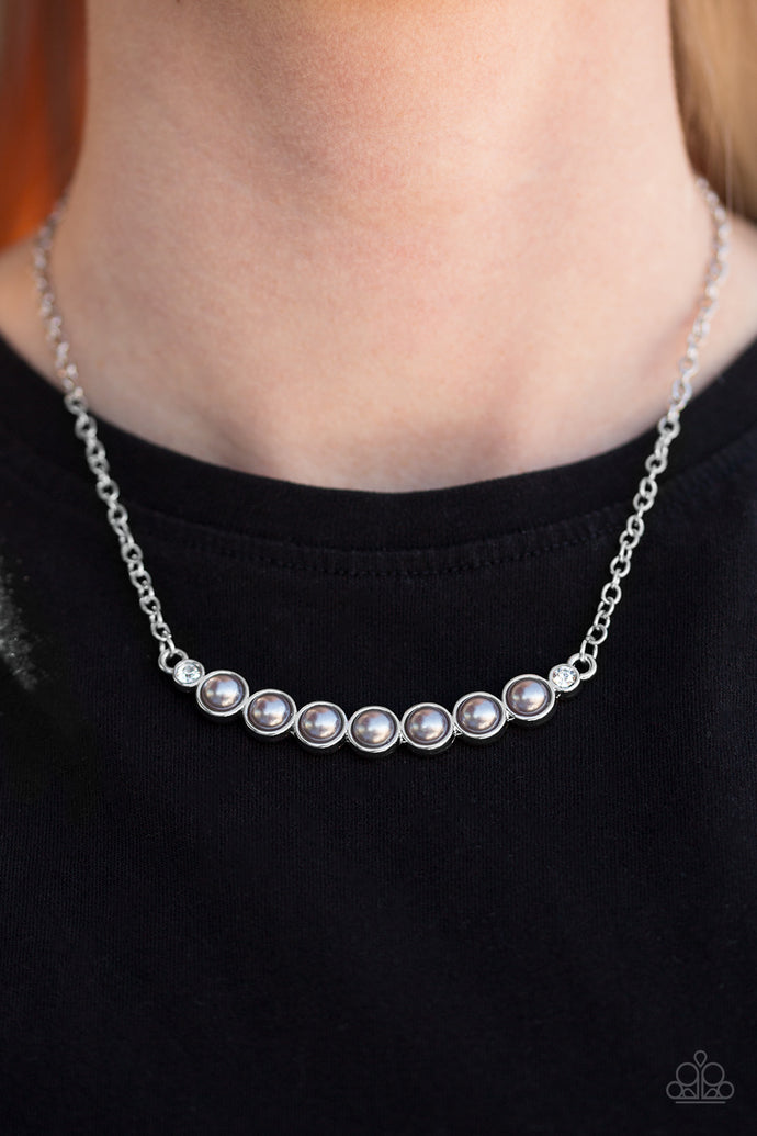A row of pearly silver beading is pressed into a slightly bowing frame, creating a refined pendant below the collar. Two glittery white rhinestones are pressed into the classy pendant for a timeless finish. Features an adjustable clasp closure.  Sold as one individual necklace. Includes one pair of matching earrings.  Always nickel and lead free.