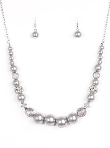 Pearly silver and glittery white crystal-like beads are threaded along the bottom of an elongated silver chain. The beads decrease in size as they climb the chain, while sparkling accents are sprinkled between them for a glamorous finish. Features an adjustable clasp closure.  Sold as one individual necklace. Includes one pair of matching earrings.