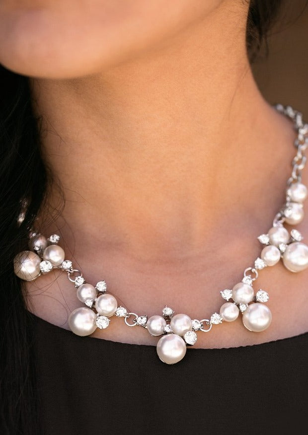 Clusters of pearls and dazzling white rhinestones join below the collar, creating refined frames. Infused with a glistening silver chain, the sections of luminescent frames trickle along the neck in a timeless fashion. Features an adjustable clasp closure.  Sold as one individual necklace. Includes one pair of matching earrings.