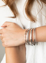 Load image into Gallery viewer, Featuring an array of smooth, hammered, and metallic rope-like textures, a mismatched collection of shiny silver bangles stacks across the wrist for a classic look.  Sold as one set of seven bracelets.  