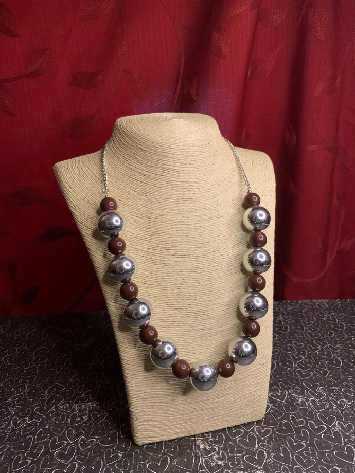 Polished brown beads and dramatic silver beads drape below the collar for a perfect pop of color. Features an adjustable clasp closure.  Sold as one individual necklace. Includes one pair of matching earrings.  Always nickel and lead free.