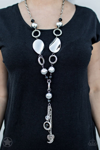 Long chain of black crystallized beads, curved plates of silver with a pearly finish, and chunky silver rings lead down to a tassel of chains and charms, including a crescent moon and a heart.  Sold as one individual necklace. Includes one pair of matching earrings.  Always nickel and lead free.  BLOCKBUSTER!