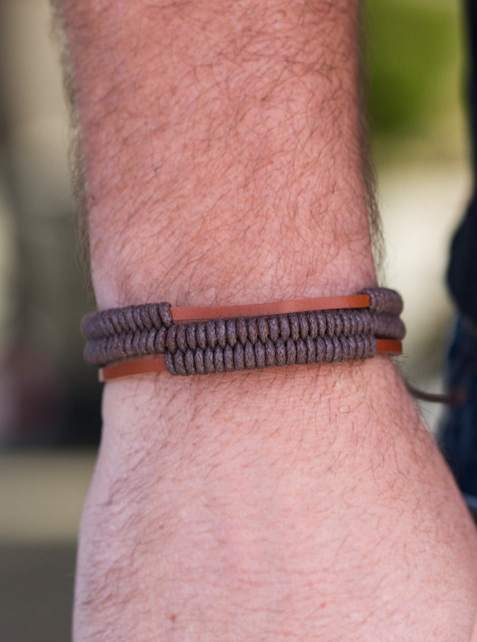 Shiny brown cords knot around three brown leather strands, securing the bands in place across the wrist for a rugged look. Features an adjustable sliding knot closure.  Sold as one individual bracelet.