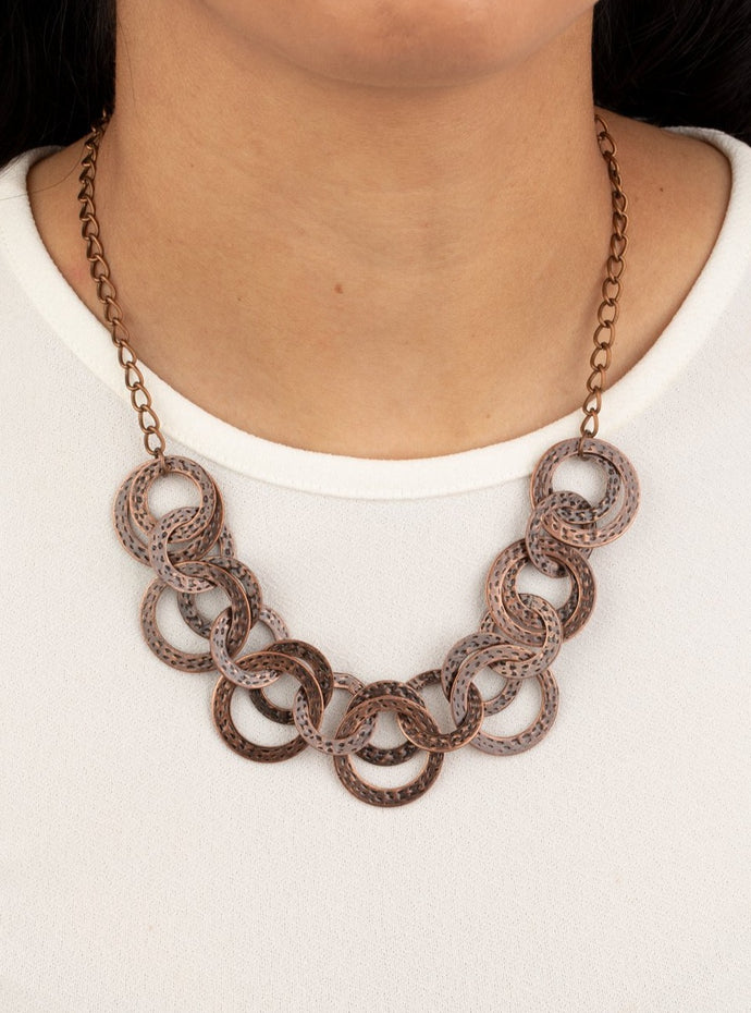 Brushed in an antiqued shimmer, delicately hammered copper discs connect below the collar for a bold industrial look. Features an adjustable clasp closure.