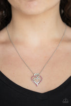 Load image into Gallery viewer, A red rhinestone encrusted heart intertwines with two plain silver heart frames, stacking into a romantic pendant at the bottom of a sleek silver chain. Features an adjustable clasp closure.  Sold as one individual necklace. Includes one pair of matching earrings.  Always nickel and lead free.