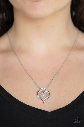 A red rhinestone encrusted heart intertwines with two plain silver heart frames, stacking into a romantic pendant at the bottom of a sleek silver chain. Features an adjustable clasp closure.  Sold as one individual necklace. Includes one pair of matching earrings.  Always nickel and lead free.