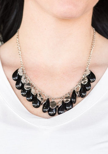 Polished black teardrops drip from the bottom of a shimmery silver chain, creating a colorful fringe below the collar. Featuring a delicately hammered surface, dainty silver teardrops are sprinkled along the chain for a splash of eye-catching shimmer. Features an adjustable clasp closure.  Sold as one individual necklace. Includes one pair of matching earrings. 