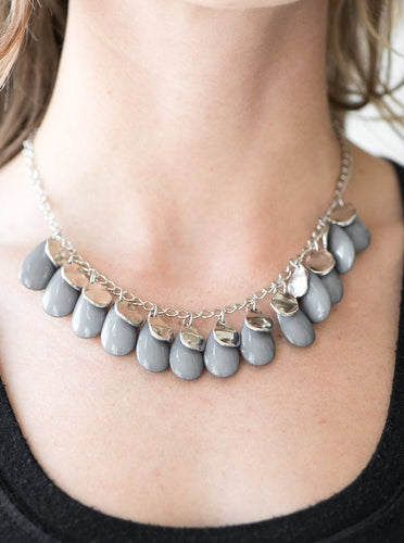 Polished gray teardrops drip from the bottom of a shimmery silver chain, creating a neutral fringe below the collar. Featuring a delicately hammered surface, dainty silver teardrops are sprinkled along the chain for a splash of eye-catching shimmer. Features an adjustable clasp closure.  Sold as one individual necklace. Includes one pair of matching earrings. 