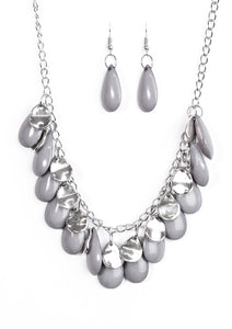 Polished gray teardrops drip from the bottom of a shimmery silver chain, creating a neutral fringe below the collar. Featuring a delicately hammered surface, dainty silver teardrops are sprinkled along the chain for a splash of eye-catching shimmer. Features an adjustable clasp closure.  Sold as one individual necklace. Includes one pair of matching earrings.