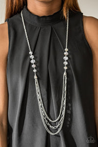 White crystal-like beads give way to layers of mismatched silver chains for a fierce look. Features an adjustable clasp closure.  Sold as one individual necklace. Includes one pair of matching earrings.