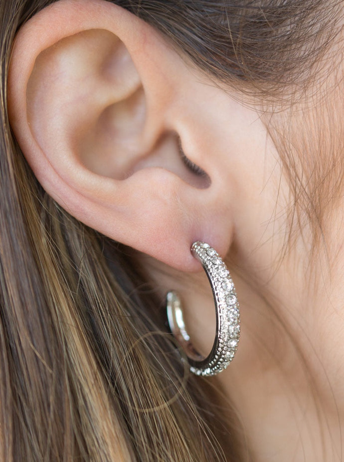 Encrusted in dazzling white rhinestones, a studded silver hoop swings from the ear for a glamorous look. Earring attaches to a standard post fitting. Hoop measures 1