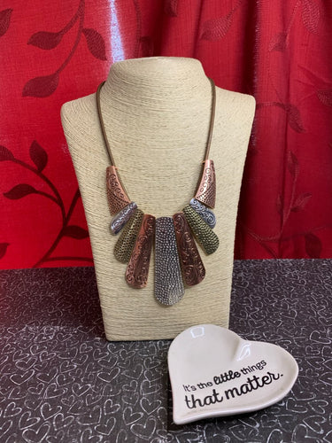 Copper, silver and brass plates featuring various hammered and filigreed textures fan out across the chest along a thick copper snake chain. The gorgeous tribal design falls gracefully below the collar into a dramatic statement piece. Features an adjustable clasp closure.  Sold as one individual necklace. Includes one pair of matching earrings.   