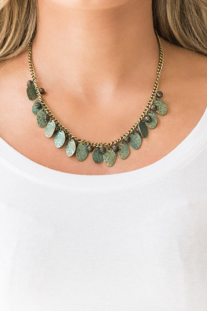 Brushed in a patina finish, floral embossed brass frames swing from a brass chain. Infused with ornate brass beads, the whimsical fringe falls just below the collar for a vintage inspired look. Features an adjustable clasp closure.  Sold as one individual necklace. Includes one pair of matching earrings.  Always nickel and lead free.