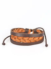 Load image into Gallery viewer, Shiny brown and orange twine weave across the wrist, creating a colorful braid. Two strands of brown leather join the colorful braid, adding earthy accents to the urban layers. Features an adjustable sliding knot closure. Sold as one individual bracelet.