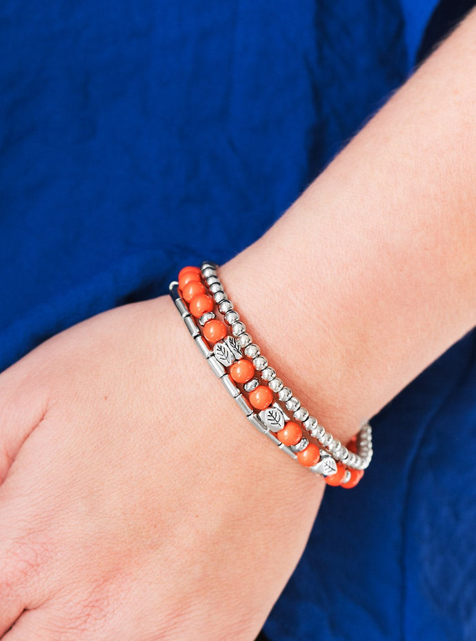 Vivacious orange beads and silver beads featuring round and cylindrical shapes are threaded along elastic stretchy bands. Stamped in tree-like patterns, faceted silver beads are sprinkled between the colorful beads for a whimsical finish.  Sold as one set of three bracelets.