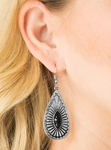 A shiny black bead is pressed into the center of a textured silver teardrop, creating a tribal inspired lure. Earring attaches to a standard fishhook fitting.  Sold as one pair of earrings.  
