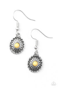 A dainty yellow bead is pressed into a shimmery silver frame radiating with floral detail