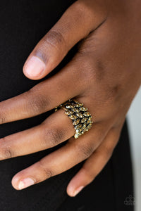 Sprinkled in glittery aurum rhinestones, the leafy brass frame vines across the finger, coalescing into a thick band. Features a stretchy band for a flexible fit.  Sold as one individual ring.  Always nickel and lead free.