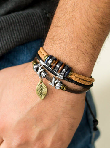Mismatched strands of leather cording layer across the wrist. Infused with wooden and metallic accents, a shimmery brass leaf charm swings from the wrist for a whimsical finish. Features an adjustable sliding knot closure.  Sold as one individual bracelet.