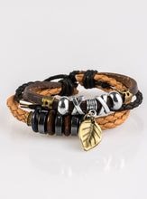 Load image into Gallery viewer, Mismatched strands of leather cording layer across the wrist. Infused with wooden and metallic accents, a shimmery brass leaf charm swings from the wrist for a whimsical finish. Features an adjustable sliding knot closure.  Sold as one individual bracelet.