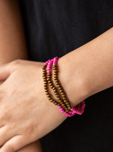 A collection of vivacious pink stones and dainty wooden beads are threaded along stretchy bands around the wrist for an earthy, layered look.  Sold as one set of three bracelets.