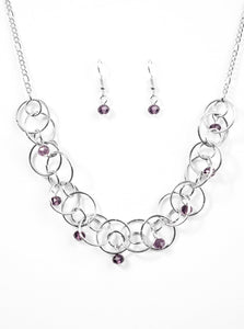 Shimmery silver hoops link below the collar, creating a bold industrial chain. Purple crystal-like beads cascade from the airy hoops for a sparkling finish. Features an adjustable clasp closure.  Sold as one individual necklace. Includes one pair of matching earrings.