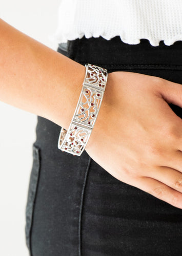 Filled with vine-like filigree, shimmery silver frames are threaded along stretchy bands around the wrist for a whimsical look. Dainty red rhinestones are sprinkled along the ornate frames for a sparkling finish.  Sold as one individual bracelet. 