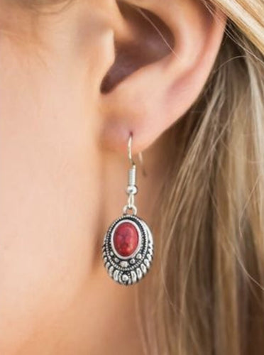A robust red bead is pressed into the center of an ornate silver frame. Glittery hematite rhinestones are sprinkled along the textured frame, adding a refined shimmer to the seasonal palette. Earring attaches to a standard fishhook fitting.  Sold as one pair of earrings.